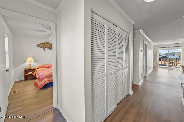 hall featuring wood-type flooring and crown molding