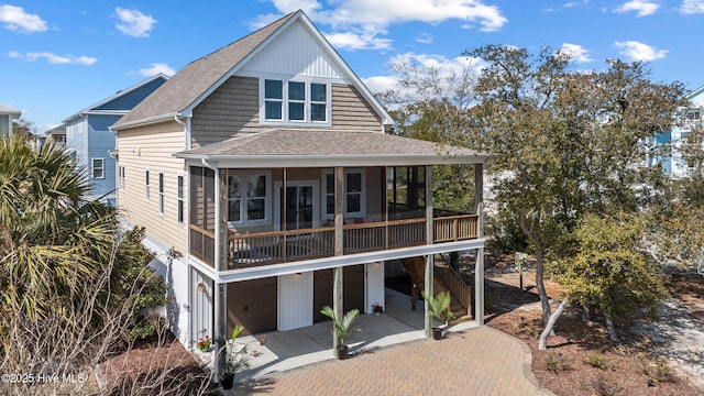 view of front of property with a patio, an attached garage, a sunroom, roof with shingles, and decorative driveway