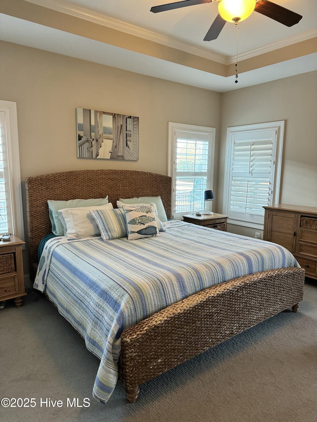 carpeted bedroom with ceiling fan, crown molding, and a raised ceiling