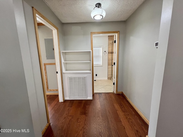 hallway with dark hardwood / wood-style floors, a textured ceiling, and electric panel