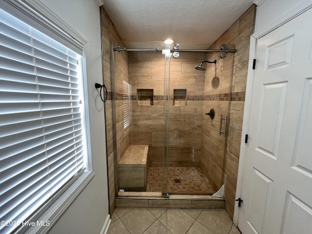 bathroom with tile patterned floors, a shower with shower door, and a textured ceiling