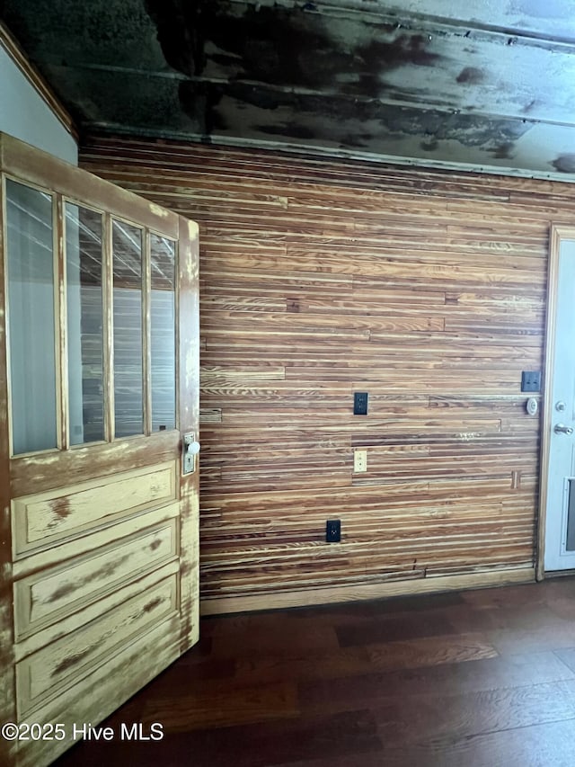 interior details with wood walls, wood-type flooring, and ornamental molding