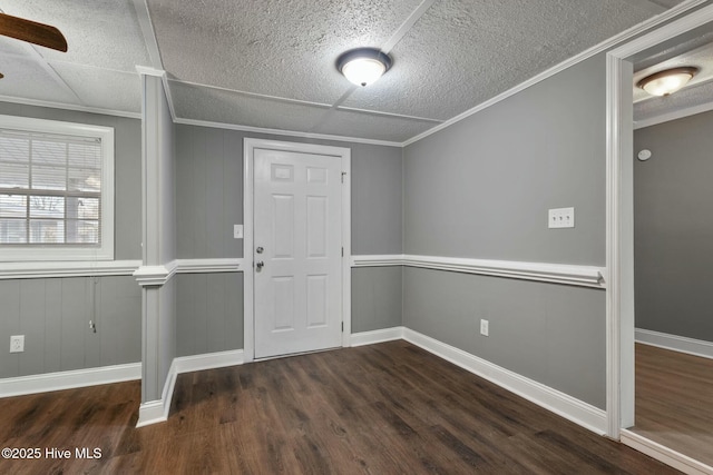 entryway with crown molding, a textured ceiling, baseboards, and wood finished floors