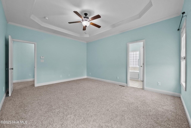 unfurnished bedroom with ceiling fan, a raised ceiling, ensuite bathroom, crown molding, and light carpet