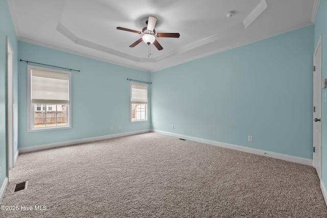 carpeted empty room featuring a raised ceiling, ceiling fan, and crown molding