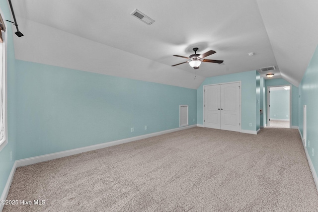 unfurnished bedroom with carpet, ceiling fan, a closet, and vaulted ceiling