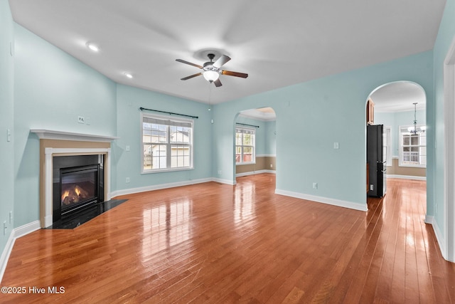 unfurnished living room featuring hardwood / wood-style floors and ceiling fan with notable chandelier