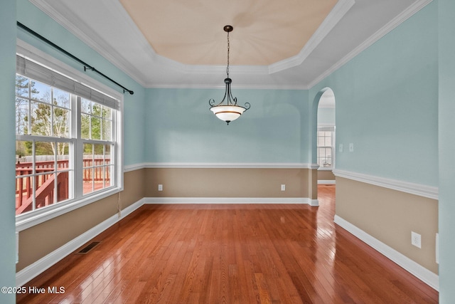 unfurnished dining area featuring a raised ceiling, wood-type flooring, and ornamental molding