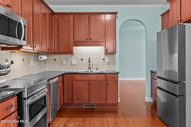 kitchen with backsplash, crown molding, sink, and appliances with stainless steel finishes