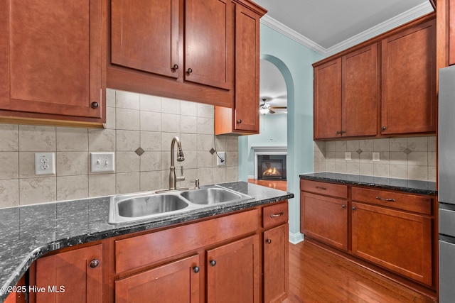 kitchen with sink, ceiling fan, decorative backsplash, ornamental molding, and light hardwood / wood-style floors