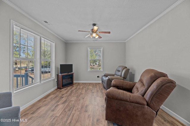 living room with ceiling fan, a fireplace, light hardwood / wood-style floors, and ornamental molding