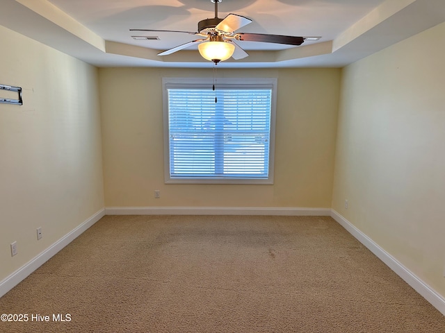 unfurnished room featuring a tray ceiling, ceiling fan, and carpet flooring