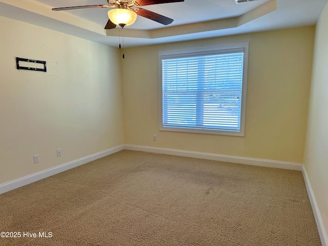 carpeted empty room featuring a tray ceiling and ceiling fan