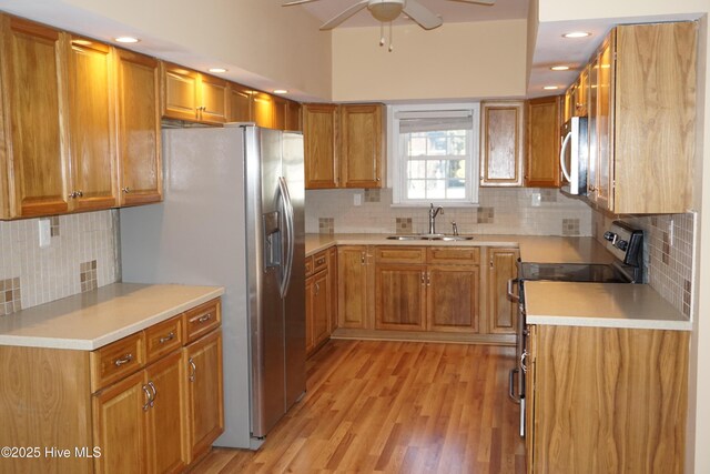 kitchen with ceiling fan, sink, light hardwood / wood-style flooring, decorative backsplash, and appliances with stainless steel finishes