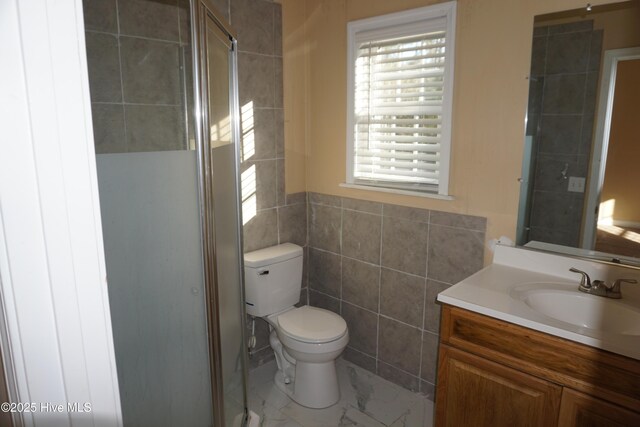 bathroom with walk in shower, vanity, toilet, and tile walls