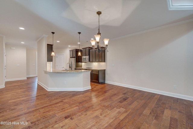 kitchen with light stone counters, crown molding, decorative light fixtures, and appliances with stainless steel finishes