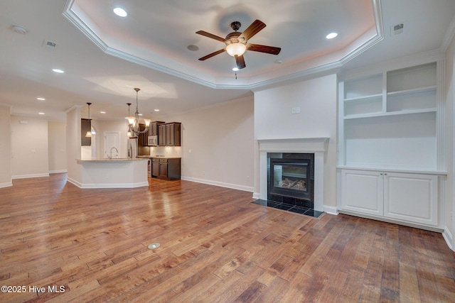 unfurnished living room featuring a tray ceiling, crown molding, and hardwood / wood-style floors