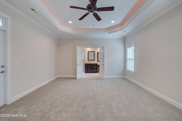 unfurnished bedroom with a tray ceiling, crown molding, ceiling fan, and light colored carpet