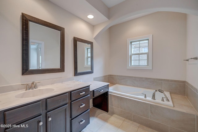 bathroom with tile patterned flooring, vanity, and a relaxing tiled tub