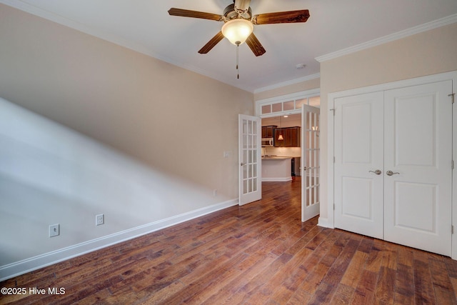 unfurnished bedroom with french doors, ornamental molding, ceiling fan, dark wood-type flooring, and a closet