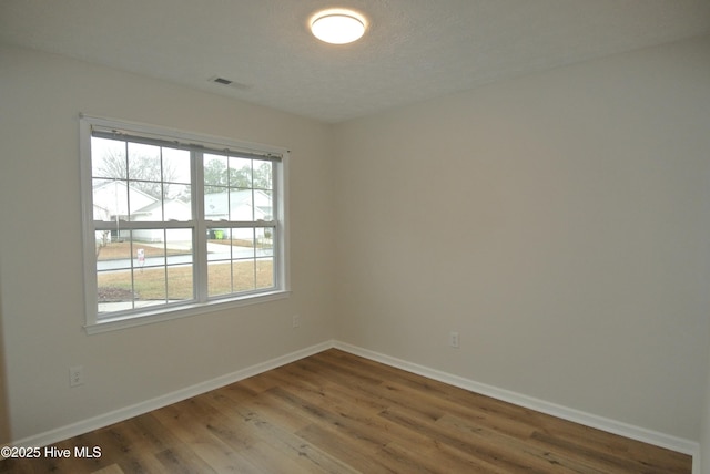 spare room featuring wood-type flooring and a textured ceiling