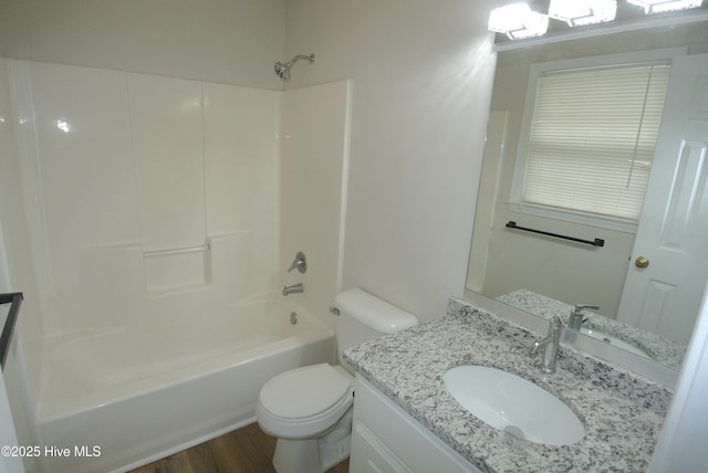 full bathroom featuring vanity, hardwood / wood-style floors, washtub / shower combination, and toilet