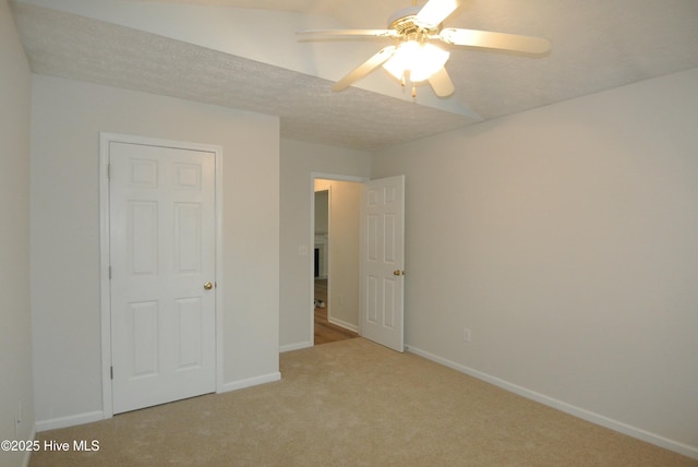 unfurnished bedroom with ceiling fan, light colored carpet, and a textured ceiling