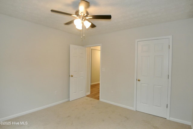 unfurnished bedroom featuring ceiling fan, light carpet, and a textured ceiling