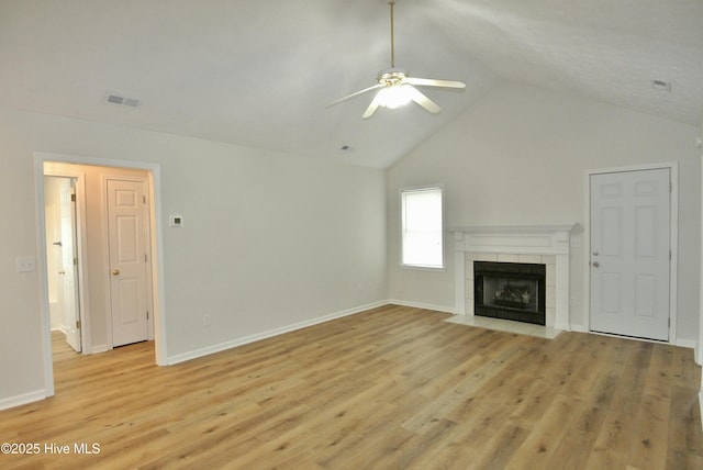 unfurnished living room with ceiling fan, high vaulted ceiling, light hardwood / wood-style floors, and a tile fireplace