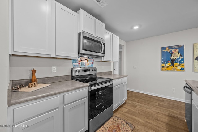 kitchen with wood-type flooring, stainless steel appliances, and white cabinetry