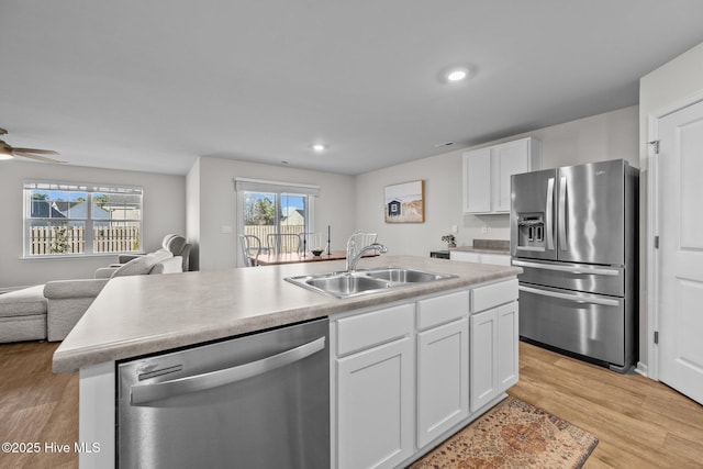 kitchen with sink, light hardwood / wood-style flooring, a center island with sink, white cabinets, and appliances with stainless steel finishes