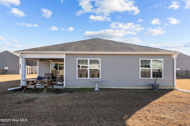 rear view of property with ceiling fan and a lawn