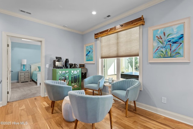 living area with light hardwood / wood-style floors and ornamental molding