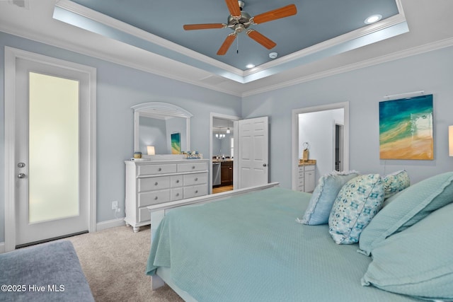 carpeted bedroom featuring ceiling fan, crown molding, a tray ceiling, and ensuite bath