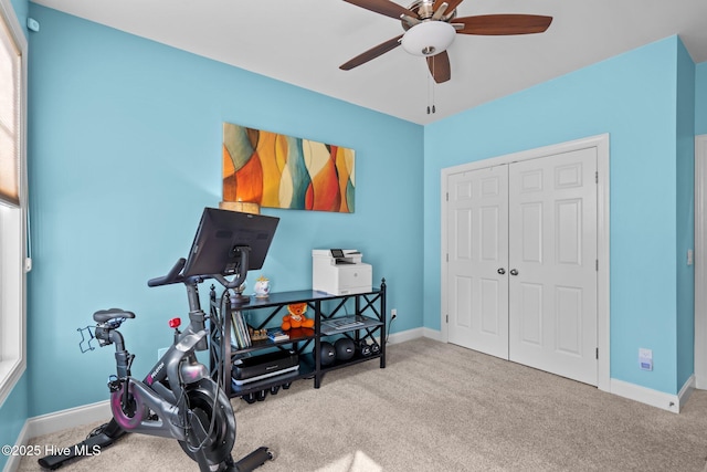 exercise room with ceiling fan and light colored carpet