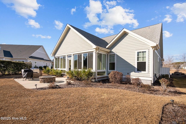 rear view of house featuring a patio area, a sunroom, a yard, and an outdoor fire pit