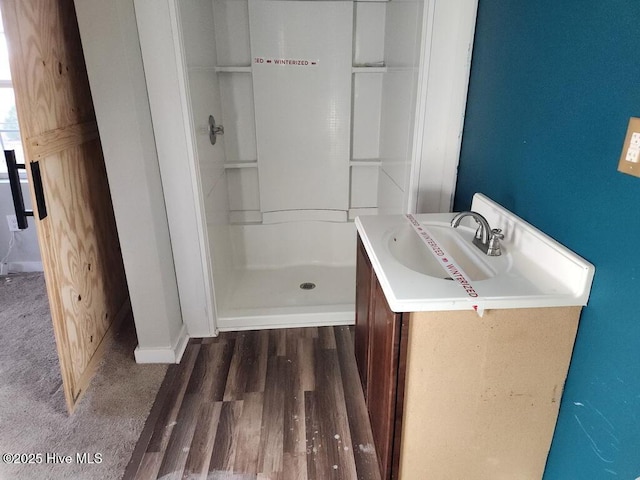 bathroom featuring wood-type flooring, vanity, and walk in shower