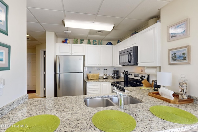 kitchen with white cabinets, backsplash, stainless steel appliances, and light stone countertops