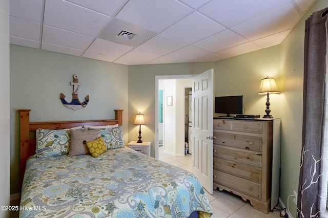 bedroom with a paneled ceiling and light tile patterned flooring