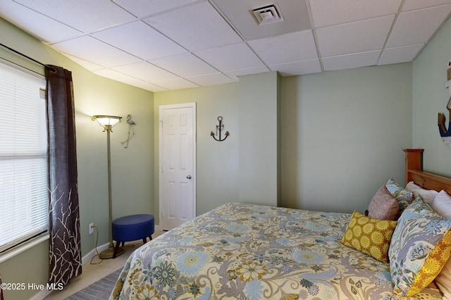 tiled bedroom featuring a paneled ceiling and multiple windows