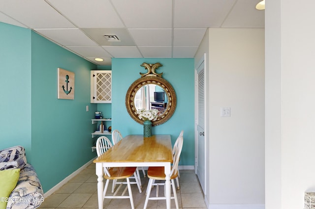 dining space featuring a drop ceiling and light tile patterned floors