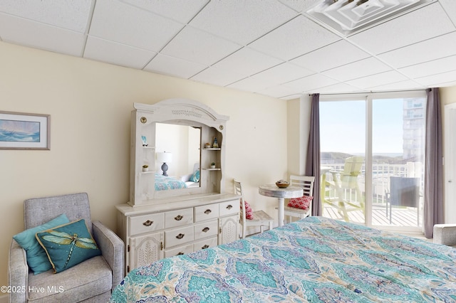 bedroom featuring access to exterior, a paneled ceiling, and a wall of windows