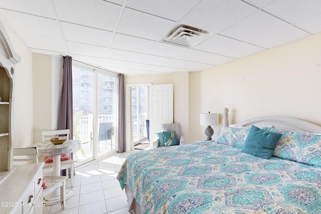 bedroom with access to exterior, light tile patterned floors, a drop ceiling, and floor to ceiling windows