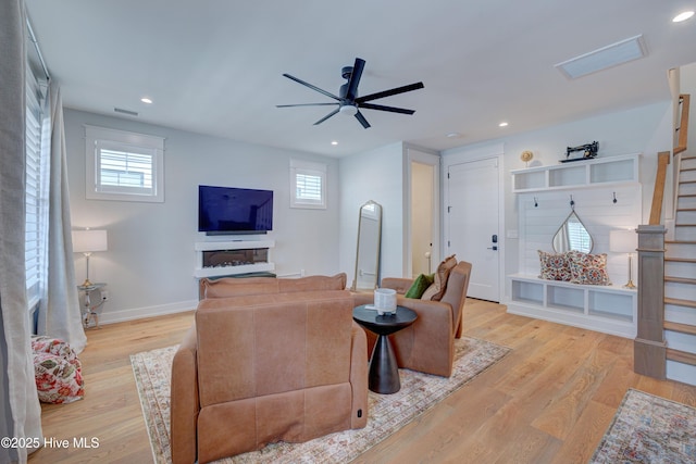 living room featuring ceiling fan, light wood-type flooring, and a wealth of natural light