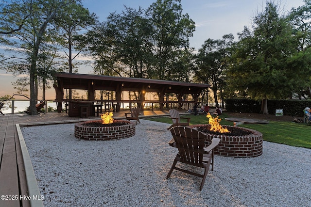 back house at dusk with a wooden deck and an outdoor fire pit