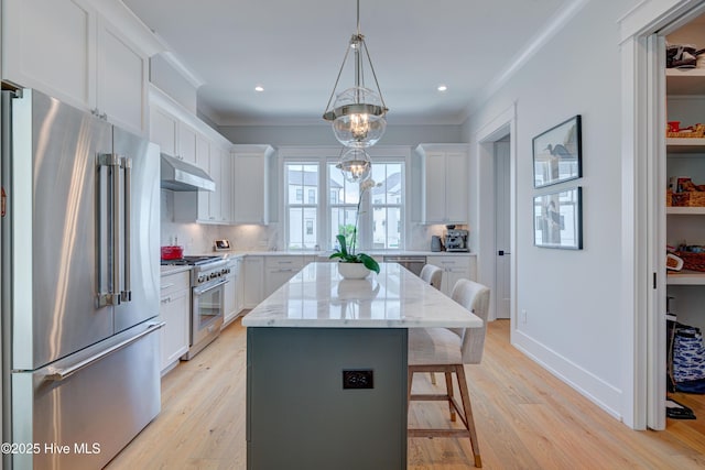 kitchen featuring high end appliances, white cabinetry, a center island, and hanging light fixtures