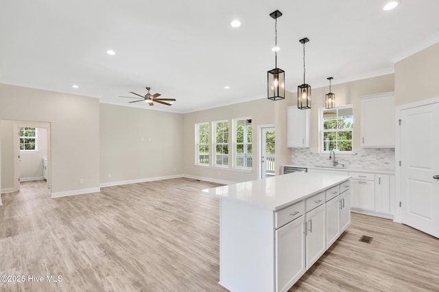 kitchen featuring a center island, white cabinets, sink, ceiling fan, and decorative light fixtures