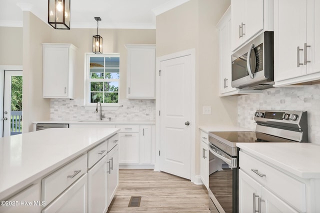 kitchen with light wood finished floors, a sink, white cabinetry, and appliances with stainless steel finishes