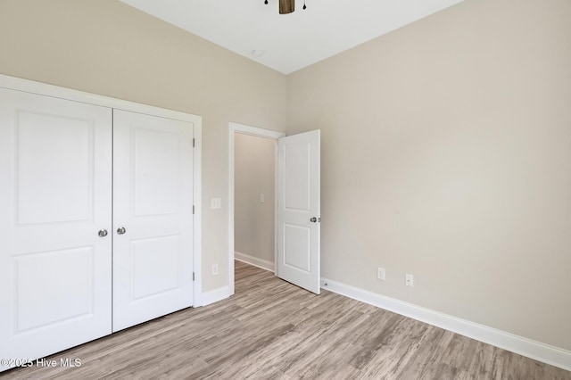 unfurnished bedroom with ceiling fan, baseboards, light wood-style floors, and a closet