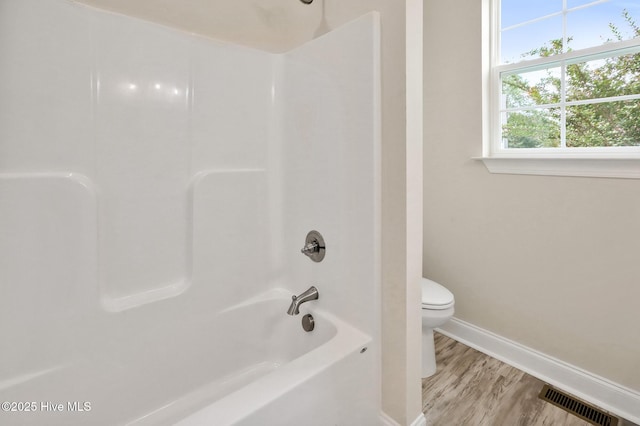 bathroom with shower / bathtub combination, baseboards, toilet, and visible vents